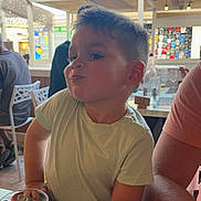 Livyo participe au concours pour gagner de l'argent avec cette photo : child, boy, table, drink, can, glass, indoor, casual, person, short_hair, tshirt, expression, mischievous, seated, restaurant, daylight, people, background, menu, arm