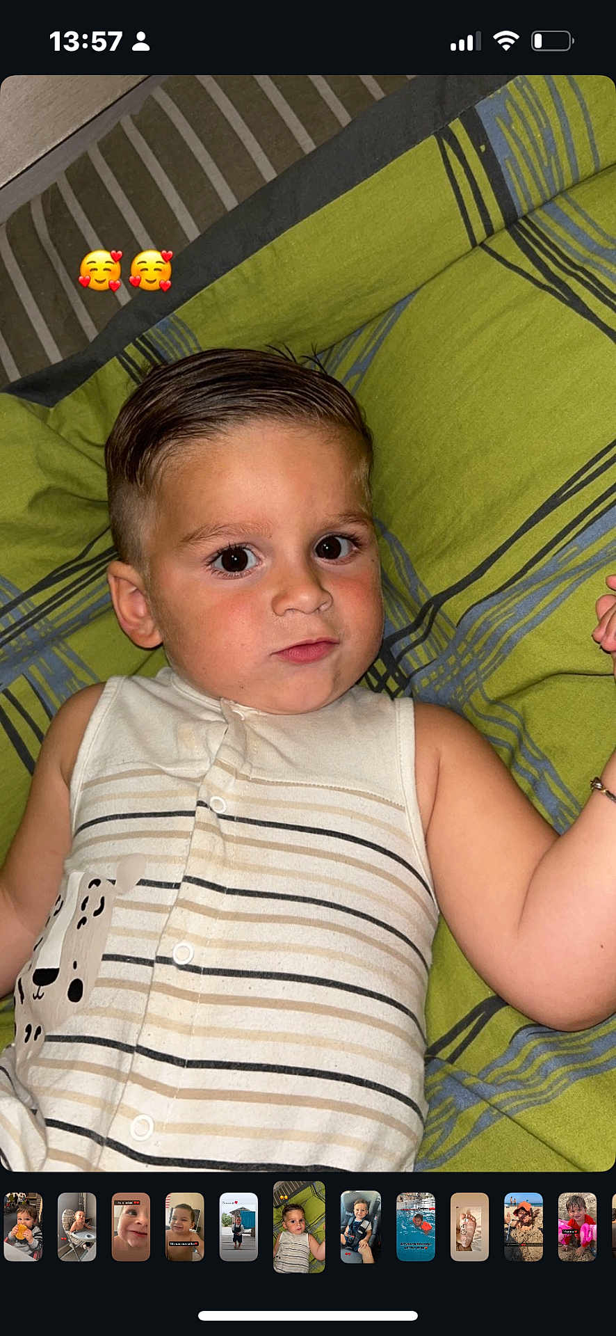 Livyo a rejoint le concours — aidez-le/la à gagner de superbes lots ! toddler, child, baby, face, hair, onesie, striped_clothing, dog_print, blanket, green_blanket, gray_stripes, lying_down, curious_expression, indoors, portrait, emoji, skin, arm, buttoned_clothing, wristband