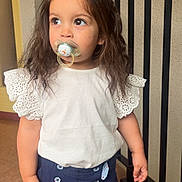 Lily-Ana participe au concours pour gagner de l'argent avec cette photo : toddler, child, pacifier, white_top, navy_shorts, standing, curly_hair, indoor, railing, floor, buttons, shorts, cute, portrait, young_child, looking_away, casual_clothing, brown_hair, small_hands, expression