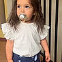toddler, child, pacifier, white_top, navy_shorts, standing, curly_hair, indoor, railing, floor, buttons, shorts, cute, portrait, young_child, looking_away, casual_clothing, brown_hair, small_hands, expression