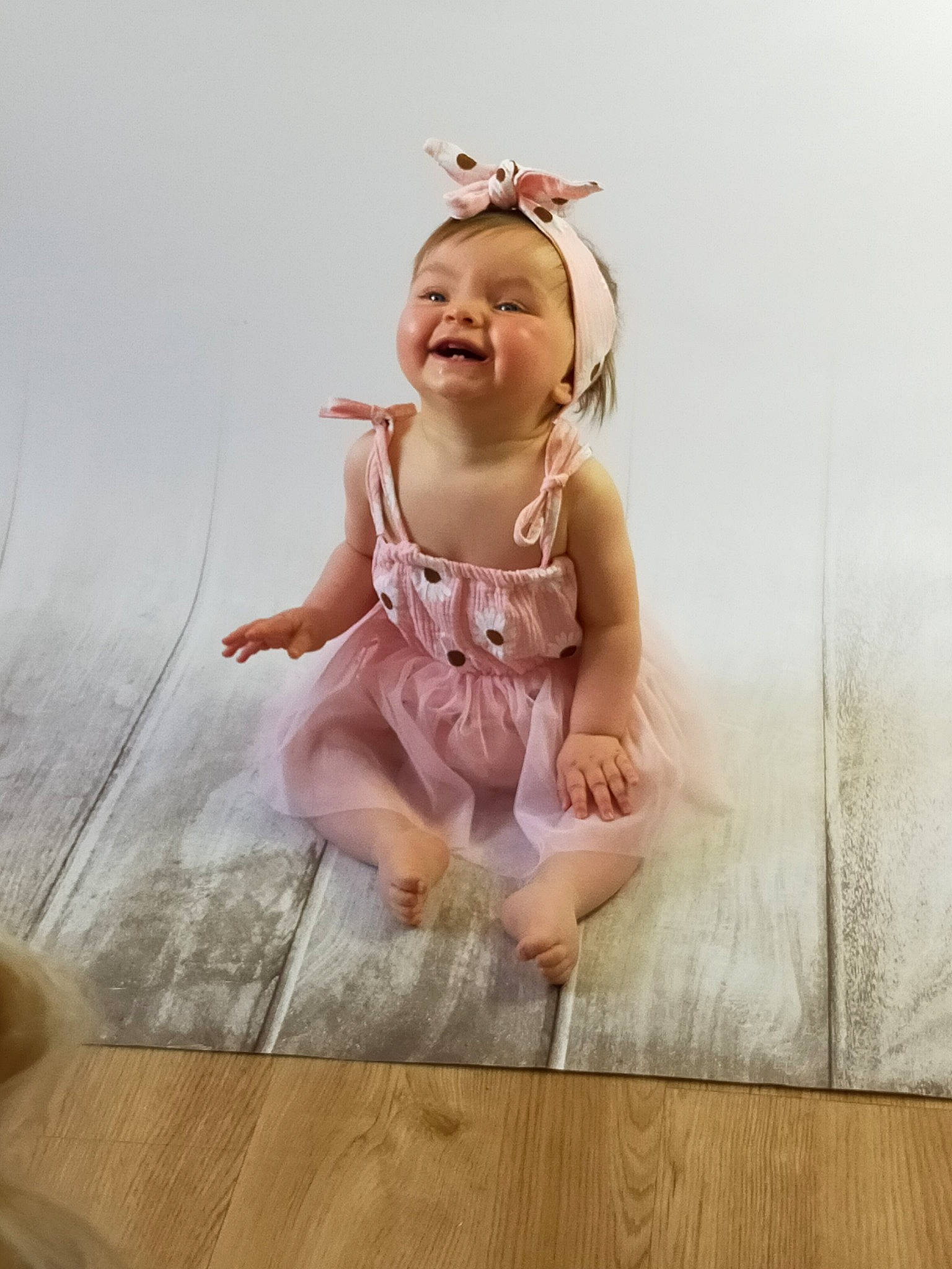 Judith participe au concours pour gagner de l'argent avec cette photo : baby, baby_toddler_clothing, dress, flash_photography, floor, flooring, foot, happy, hardwood, human_body, human_leg, iris, laminate_flooring, person, sleeve, smile, toddler, varnish, wood, wood_flooring