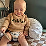 Ashton is registered to the contest to win money with this photo: baby, child, sweater, knitted, toy, wooden_toy, quilt, pillow, crib, baby_monitor, smile, happy, indoor, person, clothing, striped_diaper, head, face, furniture, home
