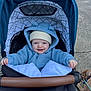 baby, child, stroller, blue_hoodie, hat, smiling, outdoor, dog, leash, pavement, happy, cute, warm_clothing, infant, person, pet, canine, blanket, hood, daylight