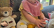 Oaklynn joined the competition — help win amazing prizes! baby, blanket, child, couch, curious, face, home, indoor, infant, mirror, natural_light, person_reflection, pink_bib, plush_toy, seated, socks, teddy_bear, toy_ball, window, yellow_clothing