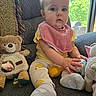 baby, blanket, child, couch, curious, face, home, indoor, infant, mirror, natural_light, person_reflection, pink_bib, plush_toy, seated, socks, teddy_bear, toy_ball, window, yellow_clothing