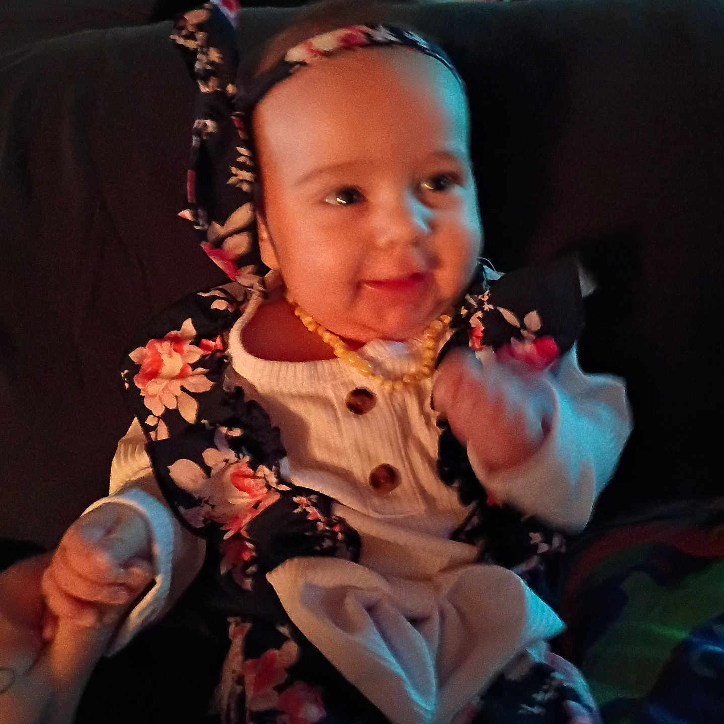 Oaklynn joined the competition — help win amazing prizes! baby, child, smiling, headband, floral_pattern, clothing, hand_holding, indoors, portrait, cute, happy, infant, person, warm_lighting, seated, long_sleeves, necklace, fabric, blurred_background, skin