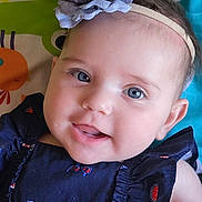 Anastasia joined the competition — help win amazing prizes! baby, child, face, blue_eyes, headband, flower, smile, navy_dress, patterned_clothing, infant, play_mat, colorful_background, cute, portrait, closeup, cheeky_expression, skin, person, young_child, happy
