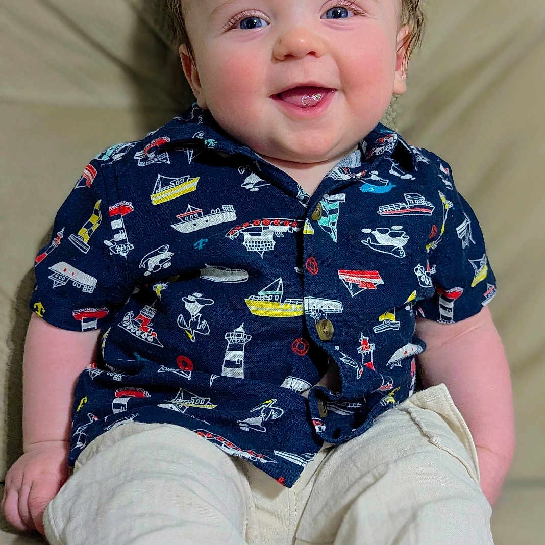 Bowie joined the competition — help win amazing prizes! baby, barefoot, blue_eyes, boat_pattern, child, clothing, cream_pants, cute, face, hands, happy, indoors, infant, navy_shirt, person, portrait, rosy_cheeks, sitting, smiling, young_child