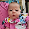 Trinity is registered to the contest to win money with this photo: baby, child, infant, pink_shirt, cartoon_clothing, person, face, cheeks, seated, portrait, outdoor, striped_chair, background, expression, skin, head, hand, candid, casual, closeup
