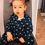 casual_wear, chair, child, curly_hair, cute, expression, floor_tiles, floral_clothing, footwear, hair_ties, home, indoor, light, person, portrait, seated, small_hands, sneakers, toddler, young_child