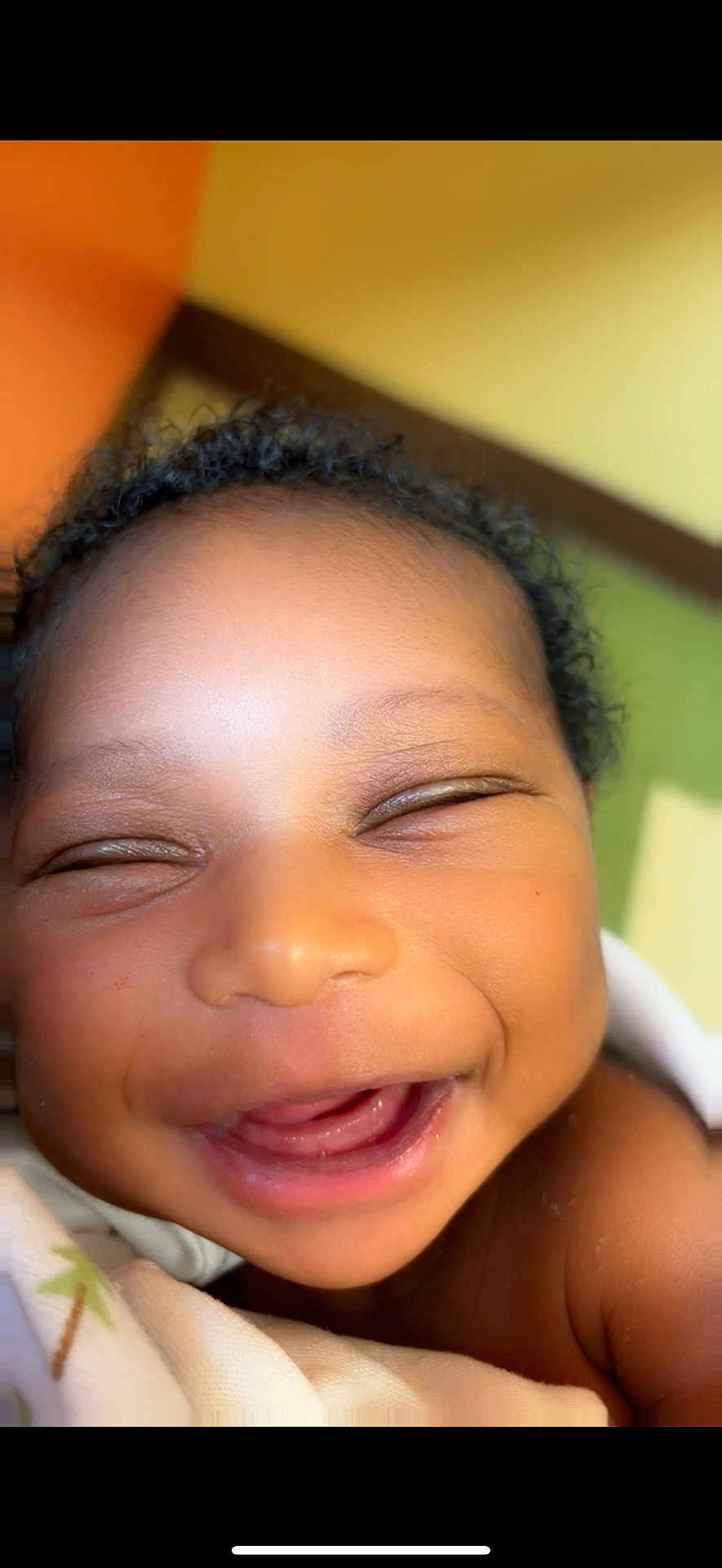 Uriah joined the competition — help win amazing prizes! baby, smiling, close_up, face, infant, joyful, blanket, skin, expression, cute, happy, child, portrait, indoors, head, young, person, natural_light, warm_colors, curly_hair