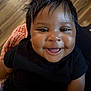 Raelynn is registered to the contest to win money with this photo: baby, smiling, face, child, black_shirt, happy, indoors, person, cute, skin, hair, blanket, floor, portrait, infant, cheerful, closeup, sitting, young, expression