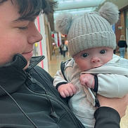 Arlo is registered to the contest to win money with this photo: baby, child, teenager, hat, pom_poms, jacket, indoor, mall, shopping_center, people, winter_clothing, cute, affection, holding, portrait, smile, face, cozy, festive_decorations, hand