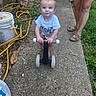toddler, child, baby, outdoor, garden, scooter, toy, sitting, standing, blue_shirt, smiling, face, portrait, adult, sandals, sidewalk, concrete, garden_hose, bucket, backyard