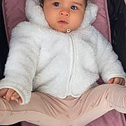 Jennah a rejoint le concours — aidez-le/la à gagner de superbes lots ! baby, child, clothing, curly_hair, cute, expression, face, hands, indoor, infant, leggings, legs, pink_cushion, portrait, seated, soft_texture, stroller, warm, white_jacket, young