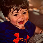 Josiah joined the competition — help win amazing prizes! toddler, smile, child, indoor, happy, blue_shirt, orange_logo, face, hair, cute, person, portrait, young_child, joy, casual_clothing, closeup, cheerful, baby, sitting, expression