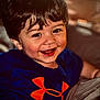 toddler, smile, child, indoor, happy, blue_shirt, orange_logo, face, hair, cute, person, portrait, young_child, joy, casual_clothing, closeup, cheerful, baby, sitting, expression