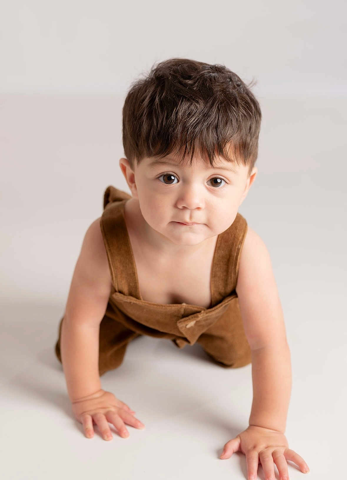 Josiah joined the competition — help win amazing prizes! toddler, child, baby, crawling, overalls, brown_clothing, curious_eyes, hair, skin, hands, floor, studio, portrait, innocent_expression, indoors, cute, young, person, clothing, face
