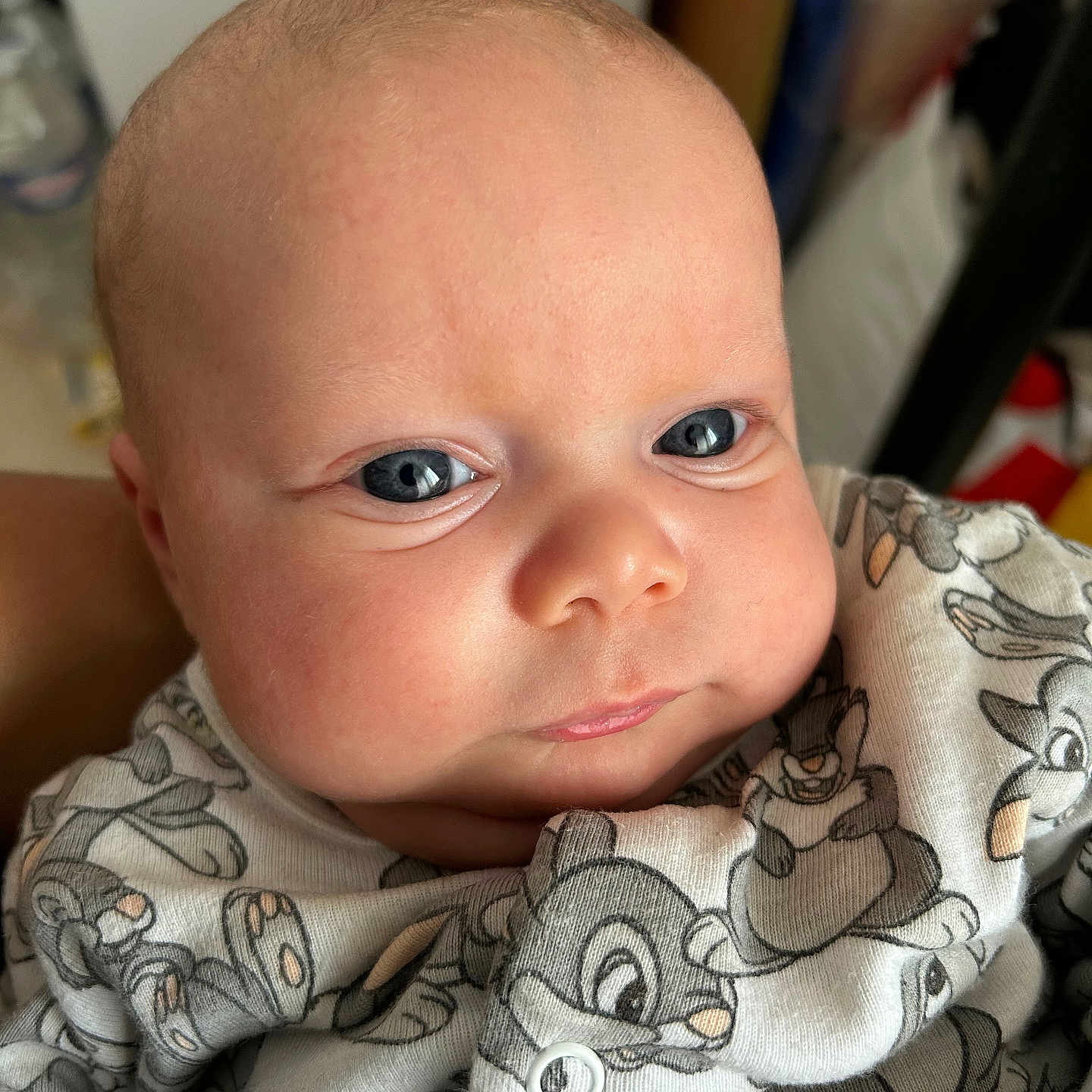 Kinika participe au concours pour gagner de l'argent avec cette photo : baby, bald_head, blue_eyes, bottle_blur, button, cartoon_print, cheeks, closeup, cute, expression, fabric, face, hand, indoor, infant, newborn, onesie, portrait, skin, soft_light