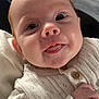baby, infant, face, eyes, sweater, knitwear, hand, skin, tongue, bubble, cute, portrait, child, young, indoor, natural_light, expression, adorable, closeup, person