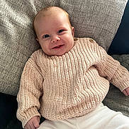 Amelia joined the competition — help win amazing prizes! baby, child, comfort, cozy, cushion, cute, face, happy, indoors, infant, knitted_sweater, person, portrait, relaxing, seated, smiling, soft_fabric, warm_clothing, white_pants, young_child
