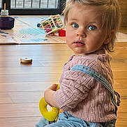 Elisabeth Mormede a rejoint le concours — aidez-le/la à gagner de superbes lots ! toddler, child, indoor, wooden_floor, toy, pink_sweater, blue_eyes, curly_hair, casual_clothing, sitting, playtime, daylight, home, window, flooring, denim_overalls, baby, cute, young_child, curious