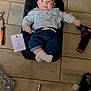 baby, infant, floor, tools, power_drill, card, clothing, socks, face, expression, wood_floor, pliers, toolbox, screwdriver_bits, jeans, shirt, black_mat, hand, smile, indoor