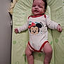 baby, infant, onesie, minnie_mouse, changing_pad, child, lying_down, cute, smiling, indoor, toddler, clothing, pattern, hair, skin, person, baby_girl, baby_boy, soft, relaxed