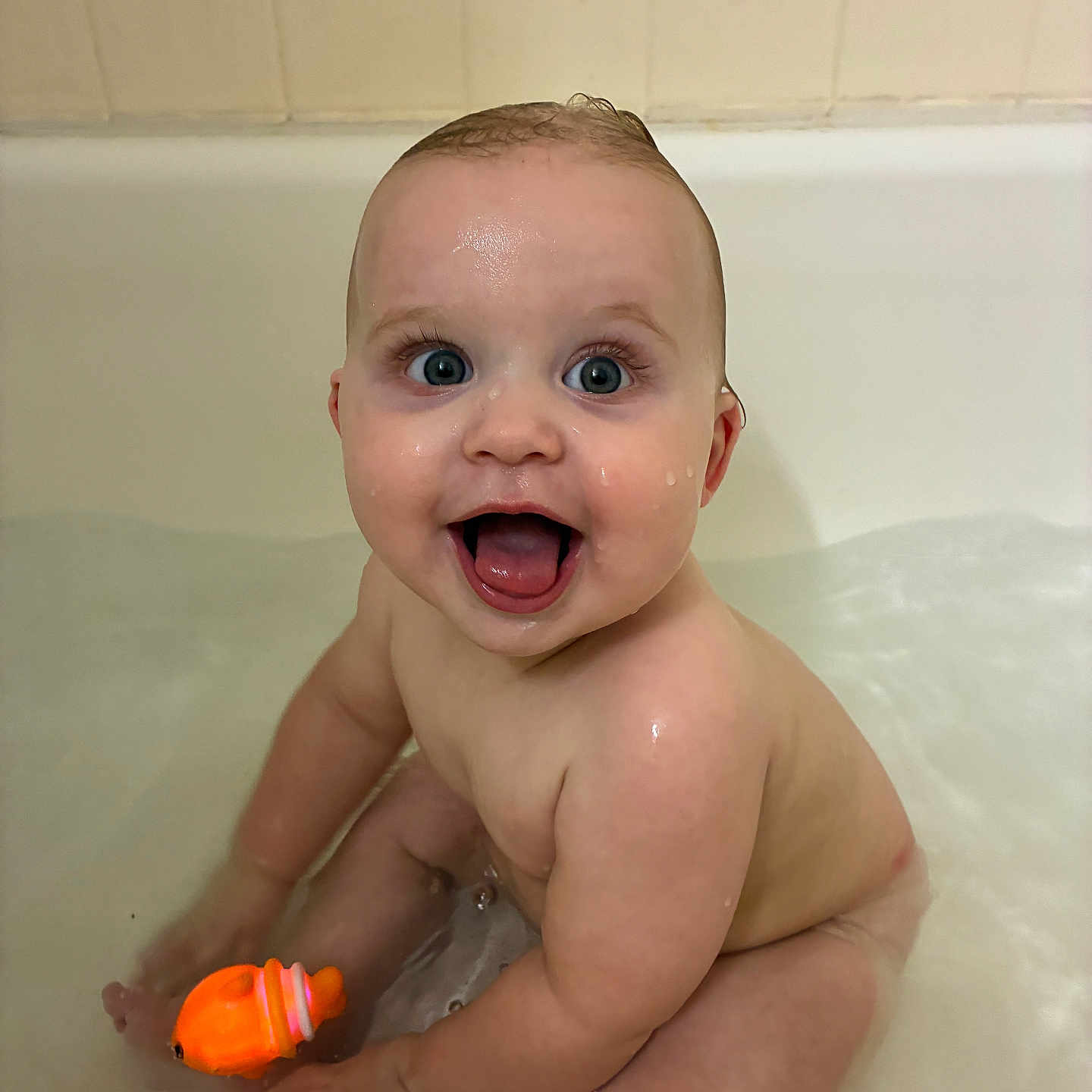 Landon is registered to the contest to win money with this photo: baby, bathtub, water, toy, orange, child, happy, smiling, sitting, skin, blue_eyes, wet, playful, indoor, cute, infant, bath_time, water_droplets, person, young_child