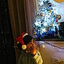 child, toddler, santa_hat, christmas_tree, holiday, festive, decorations, lights, indoors, cozy, curtain, face, person, winter, seasonal, home, cute, young_child, soft_lighting, celebration
