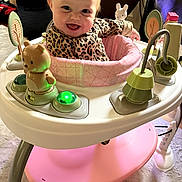 Stormi joined the competition — help win amazing prizes! baby, child, smile, leopard_print, walker, toy, indoor, happy, face, person, playful, infant, clothing, furniture, floor, activity_center, bright, cute, seat, expression