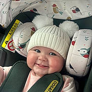 Iris joined the competition — help win amazing prizes! baby, car_seat, hat, smile, child, infant, pom_poms, clothing, seatbelt, bird_pattern, cute, cheeks, pink_shirt, safety, headwear, indoor, happy, young_child, cozy, portrait