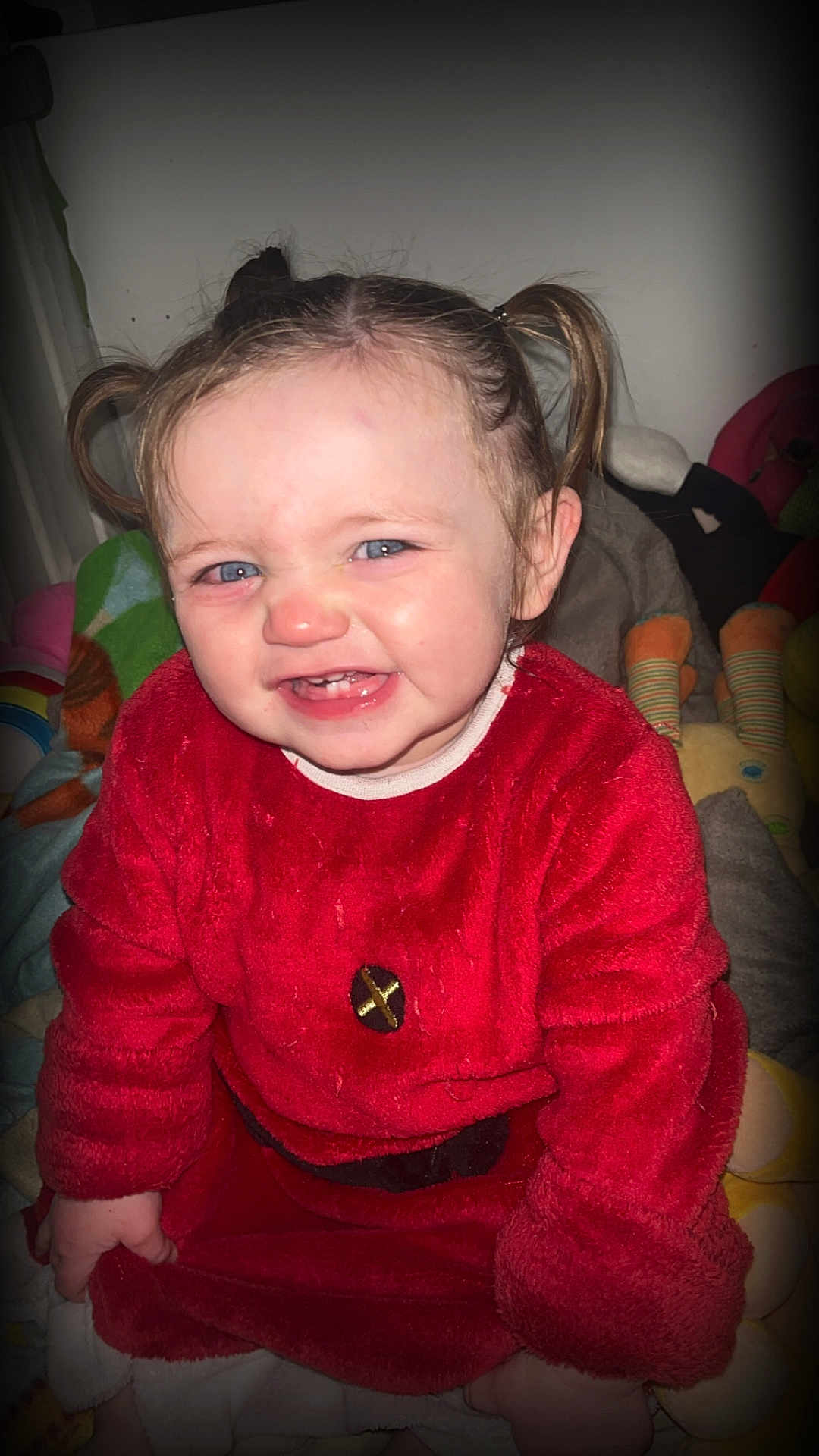 Kayana participe au concours pour gagner de l'argent avec cette photo : child, toddler, smiling, red_clothing, pigtails, blue_eyes, indoors, soft_toys, blanket, cute, face, happy, young_child, sitting, portrait, cozy, baby, playful, person, expression