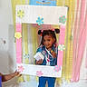 Amora joined the competition — help win amazing prizes! child, girl, smiling, portrait, standing, indoor, easter, spring, party, decoration, flowers, pastel, streamers, balloons, cardboard_frame, purse, denim_jacket, jeans, white_shoes, wooden_floor