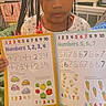 Amora joined the competition — help win amazing prizes! child, preschooler, girl, portrait, indoors, bedroom, braids, beads, hair_accessories, workbook, homework, numbers, counting, education, learning, colorful, sitting, blanket, furniture, schoolwork