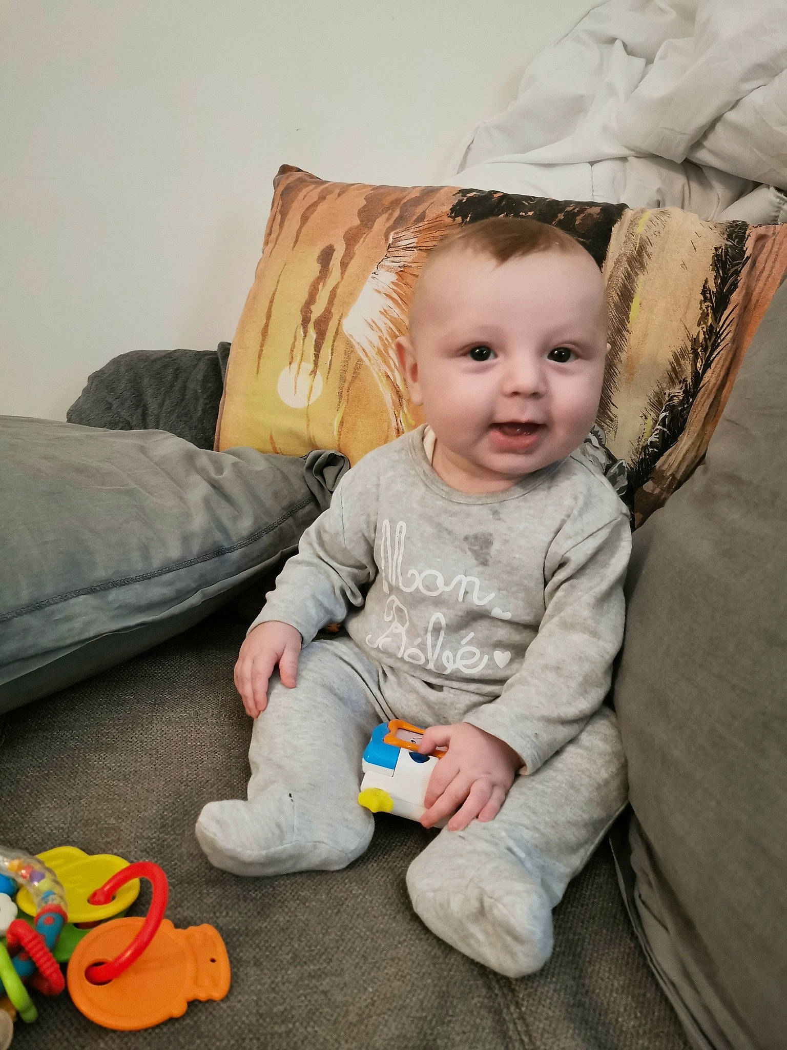 Ethan participe au concours pour gagner de l'argent avec cette photo : baby, baby_playing_with_toys, baby_products, baby_toddler_clothing, baby_toys, cheek, child, comfort, couch, eye, home_accessories, living_room, person, pillow, plush, product, sitting, stuffed_toy, throw_pillow, toddler