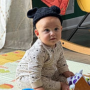 Danilo joined the competition — help win amazing prizes! baby, child, infant, portrait, sitting, indoors, playroom, toys, toy_mat, bear_hat, knit_hat, onesie, patterned_clothing, wide_eyes, looking_at_camera, face, hands, feet, colorful, home