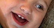 Danilo joined the competition — help win amazing prizes! baby, child, infant, smiling, happy, close_up, portrait, face, eyes, teeth, tooth, mouth, cheeks, head, indoor, blanket, clothing, green_shirt, reclining, photography
