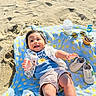 baby, smiling, beach, sand, blanket, hat, baby_shoes, bottle, sunglasses, cupcake, birthday_candle, sunlight, happy, child, clothing, outdoor, celebration, footwear, infant, playful