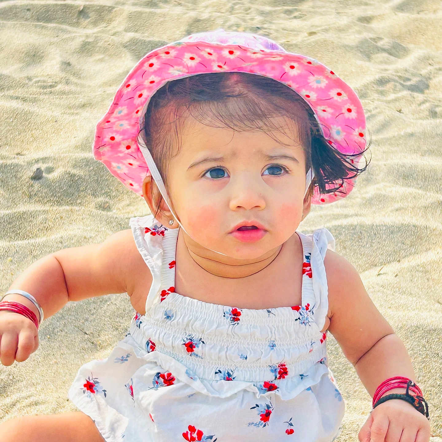 Ariana is registered to the contest to win money with this photo: accessories, baby, beach, beachwear, clothing, coast, face, hat, head, nature, outdoors, person, photography, portrait, sea, shoreline, sitting, summer, sunhat, water