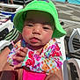 baby, bucket_hat, child, daylight, floral_pattern, hand, hat, legs, lounge_chair, outdoor, people, person, poolside, recreation, relaxing, skin, summer, sunny, swimsuit, water