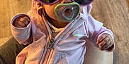 Khylan joined the competition — help win amazing prizes! baby, infant, pacifier, sunglasses, pink_clothing, onesie, hand, lap, flooring, person, cute, indoor, child, feet, sitting, casual, relaxed, accessory, human, portrait