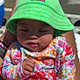 baby, blue, bright_colors, bucket_hat, child, chubby_cheeks, colorful, cute, floral_clothing, green_hat, hat, infant, outdoor, person, pink, poolside, sitting, skin, summer, sunlight