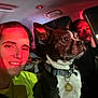 dog, boston_terrier, person, car, seatbelt, collar, tag, indoor, night, red_light, smile, face, pet, animal, vehicle_interior, human, portrait, candid, companion, closeup