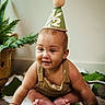 baby, child, party_hat, half_birthday, smiling, sitting, indoors, plant, blanket, floor, cute, portrait, happy, young_child, casual_clothing, crawling, green, decor, infant, celebration