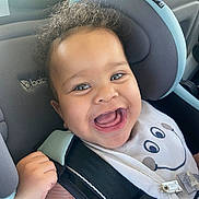 Hunter is registered to the contest to win money with this photo: baby, car_seat, child, curly_hair, smiling, happy, bib, clothing, seatbelt, closeup, indoor, cute, infant, person, face, cheeks, pink_shirt, car_interior, joyful, expression