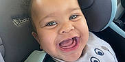 Hunter is registered to the contest to win money with this photo: baby, bib, car_interior, car_seat, cheeks, child, closeup, clothing, curly_hair, cute, expression, face, happy, indoor, infant, joyful, person, pink_shirt, seatbelt, smiling