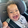 baby, car_seat, child, curly_hair, smiling, happy, bib, clothing, seatbelt, closeup, indoor, cute, infant, person, face, cheeks, pink_shirt, car_interior, joyful, expression