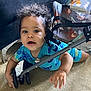 toddler, child, baby, curly_hair, blue_clothing, crawling, stroller, wheel, carpet, indoor, hand, face, expression, curious, person, young_child, play, floor, bright_eyes, casual