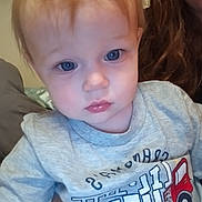 Eryn joined the competition — help win amazing prizes! toddler, child, blue_eyes, grey_shirt, fire_truck, text_on_clothing, person, indoor, close_up, baby, face, hair, lip_gloss, adult_hand, curious, casual_clothing, portrait, young_child, human, soft_lighting